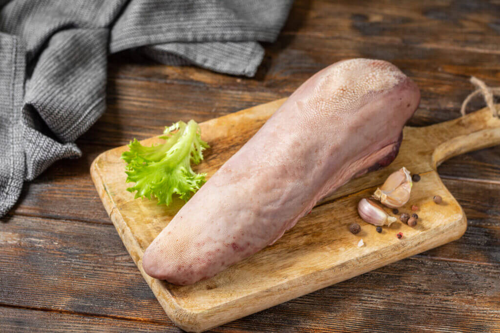 Beef tongue on a wooden Board on a brown wooden table.