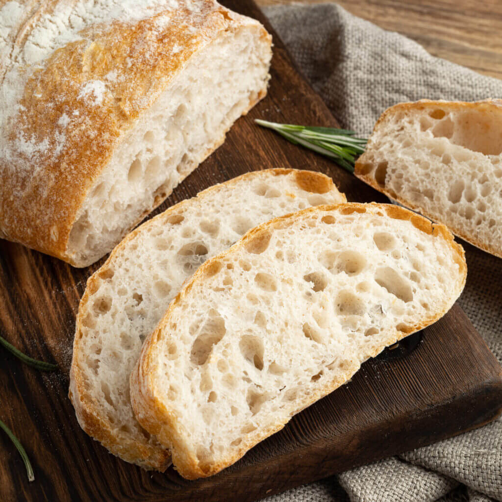 Delicious homemade sliced Italian ciabatta bread on a wooden cutting board. Close-up.