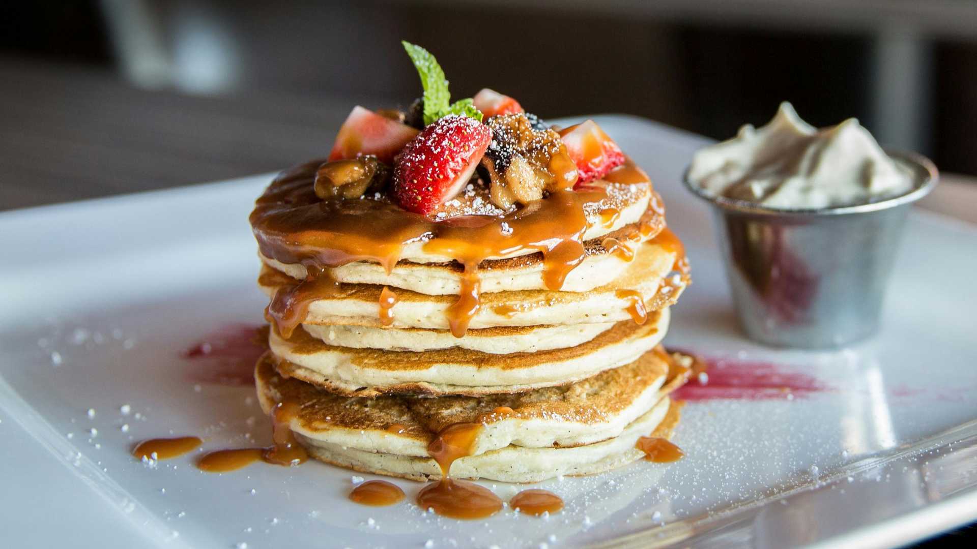 Pancakes topped with sliced strawberries on a plate