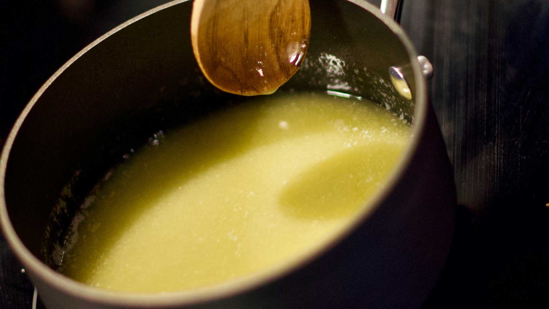 Soup or melted butter in a black bowl with a wooden surface