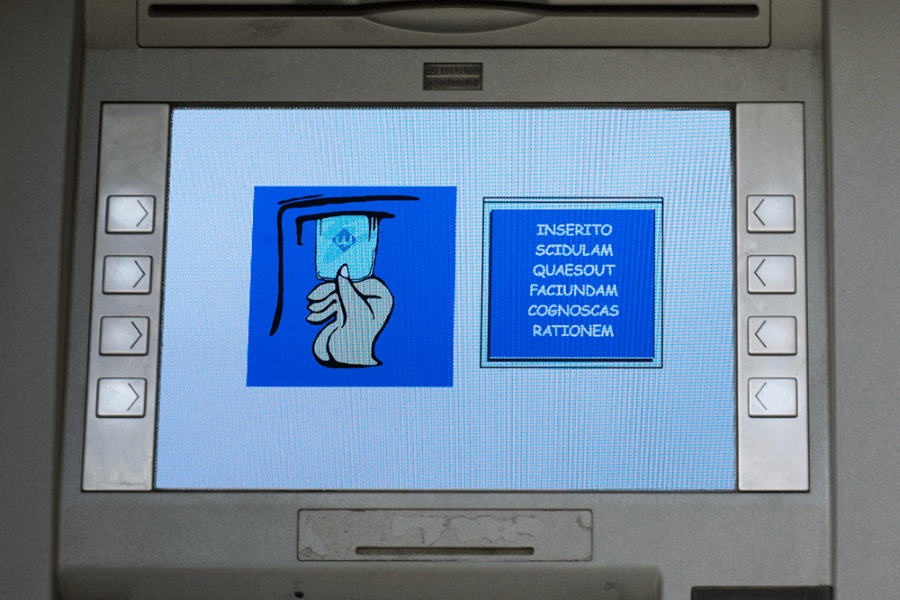 Close-up of an ATM screen in the Vatican displaying instructions in Latin, with a graphic of a hand inserting a card on the left and the Latin text "INSERITO SCIDULAM QUAESO UT FACIUNDAM COGNOSCAS RATIONEM" on the right, which roughly translates to "Please insert your card to proceed."