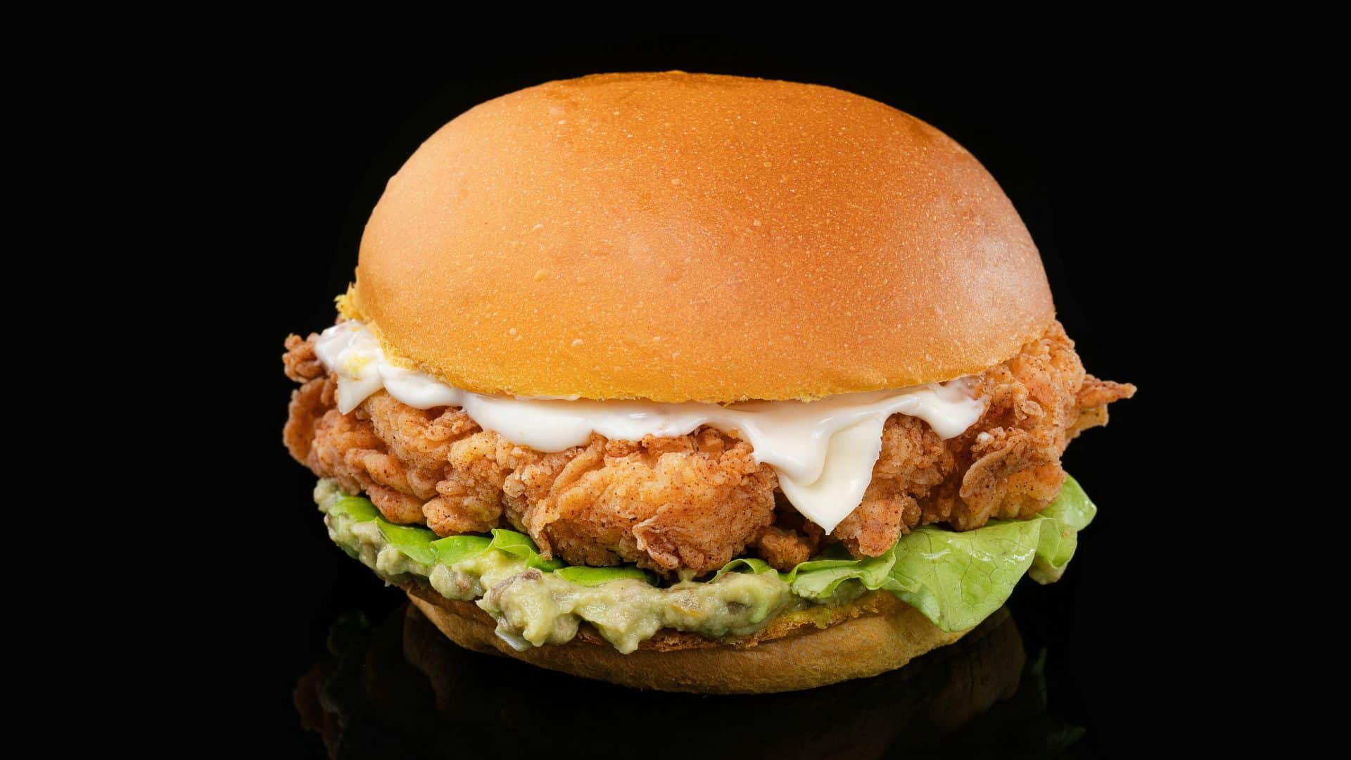 Chicken sandwich with lettuce and mayonnaise on a black background