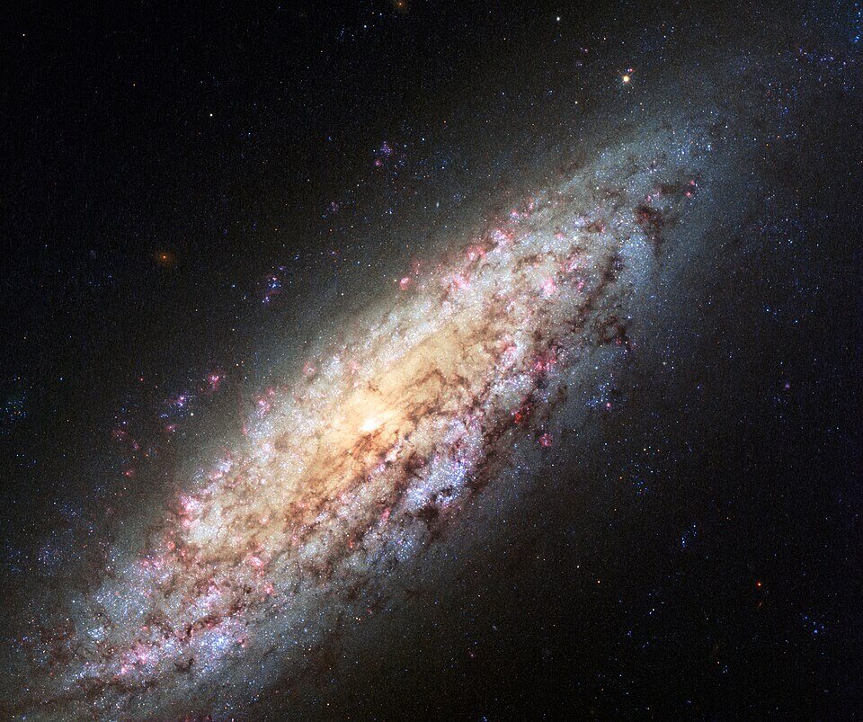 A detailed image of a spiral galaxy glowing with golden, pink, and blue hues, surrounded by countless stars against the blackness of space.