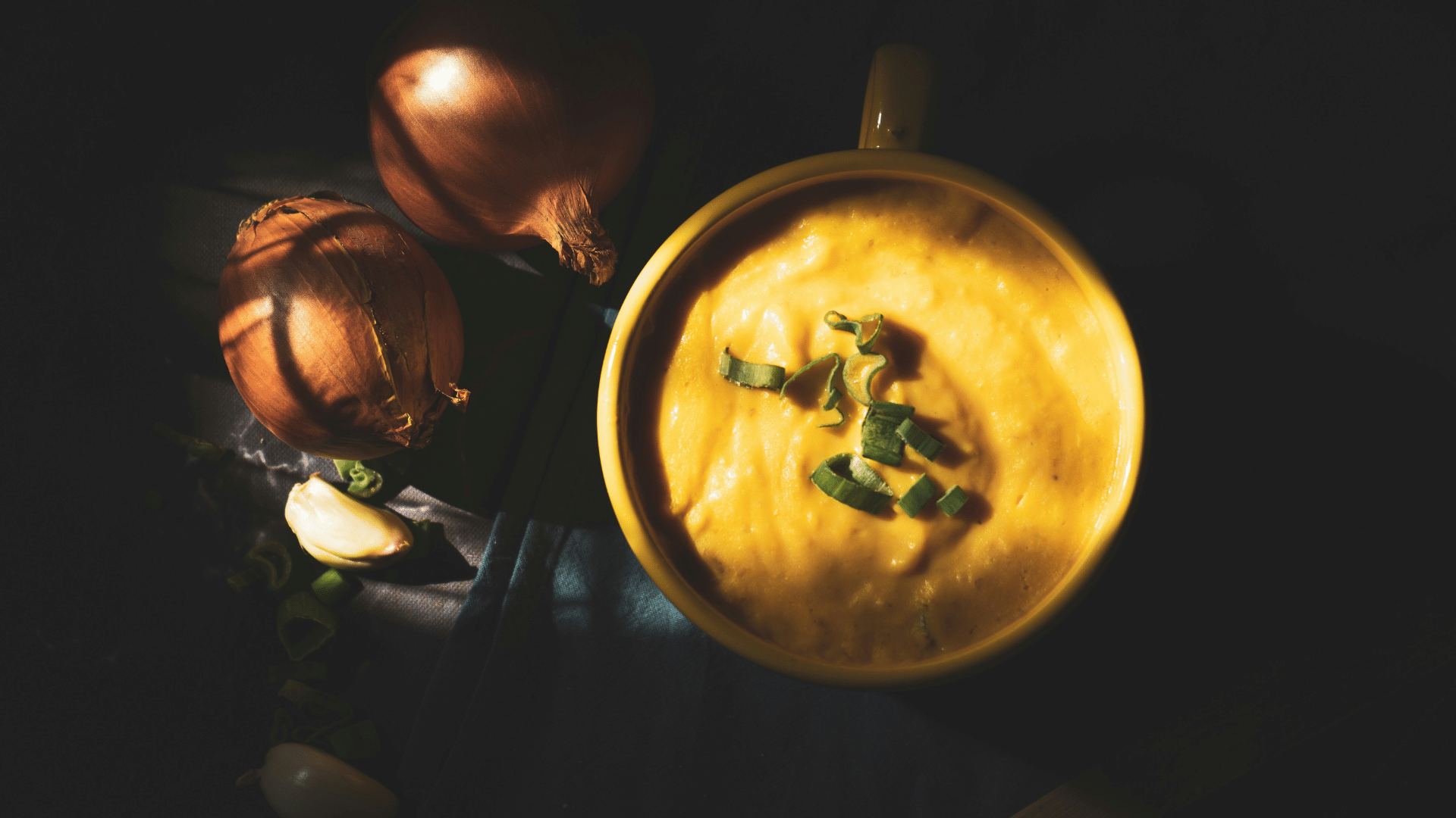 Man holding a stainless steel bowl filled with soup in a kitchen