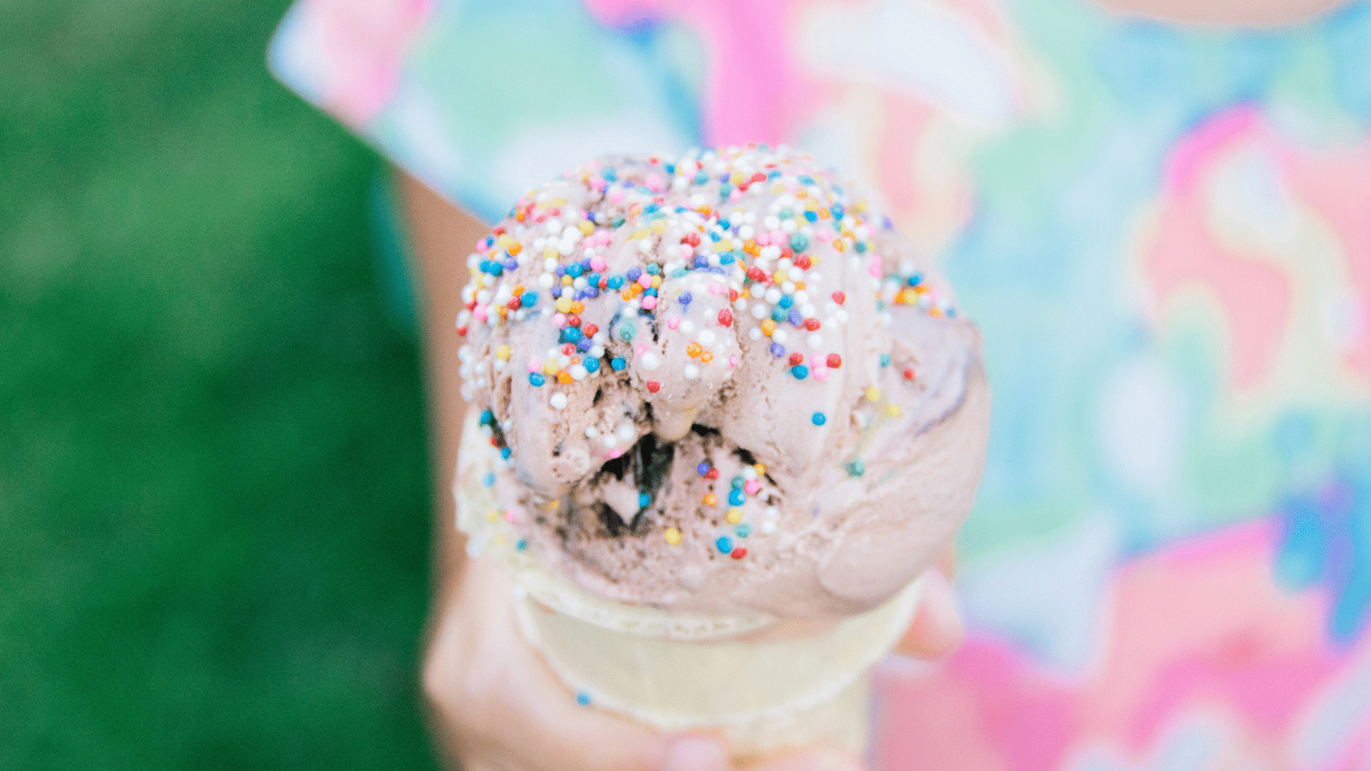 Child holding an ice cream cone with colorful sprinkles