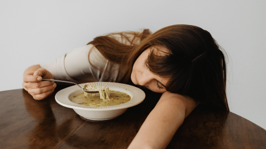 Woman looking down while eating soup with a spoon