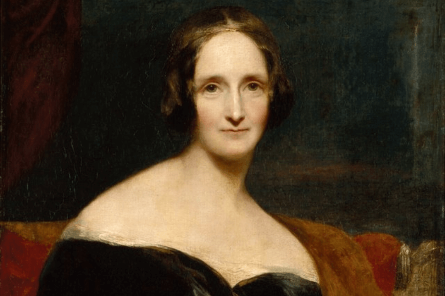 A classical oil painting of a woman with dark brown hair styled in soft curls, wearing an elegant black off-the-shoulder dress. Her expression is calm and composed, with a gentle gaze directed at the viewer. The background is dark and muted, with warm tones in the drapery and fabric enhancing the portrait’s refined atmosphere.