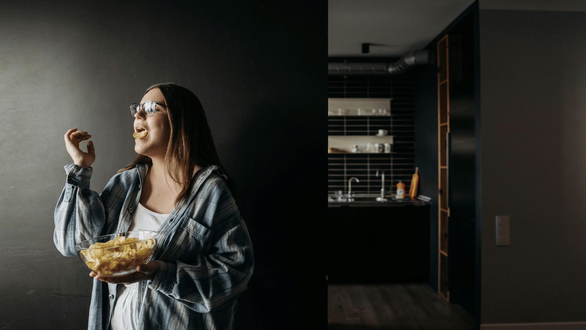 Woman in a plaid shirt smiling while holding a large bowl of chips