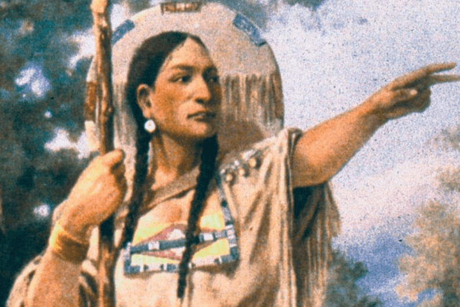 A historical illustration of a woman in traditional Indigenous attire, holding a staff and pointing forward with a determined expression. She wears a beaded and fringed garment, with her hair in two long braids and a decorated shield on her back. The background features a natural outdoor setting with soft blue skies and trees.