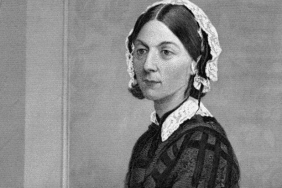A black-and-white portrait of a woman dressed in a modest, high-collared gown with a lace-trimmed cap. Her hair is neatly parted in the middle and pulled back, and she has a composed expression with a calm gaze. The soft, neutral background emphasizes her dignified and refined presence.