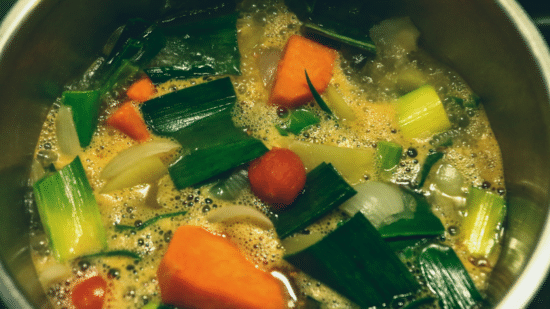 Vegetable stew served in a black bowl on a wooden table