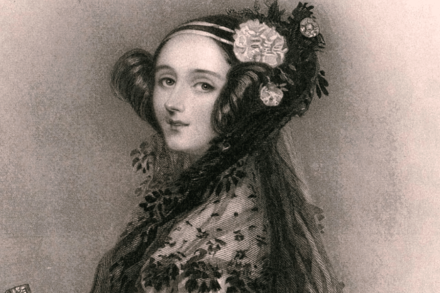 A vintage black-and-white portrait of a woman from the 19th century, elegantly dressed with intricate curls framing her face. She wears a decorative headpiece adorned with flowers and jewels, and a lace-trimmed gown with a delicate shawl. Her gaze is poised and confident, reflecting a refined and intellectual presence.