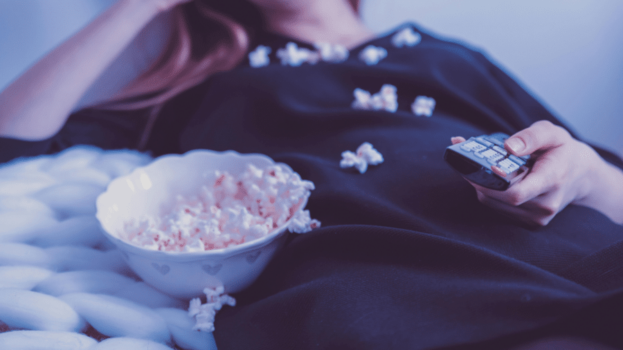 Woman wearing a black shirt eating popcorn alone in a dark room