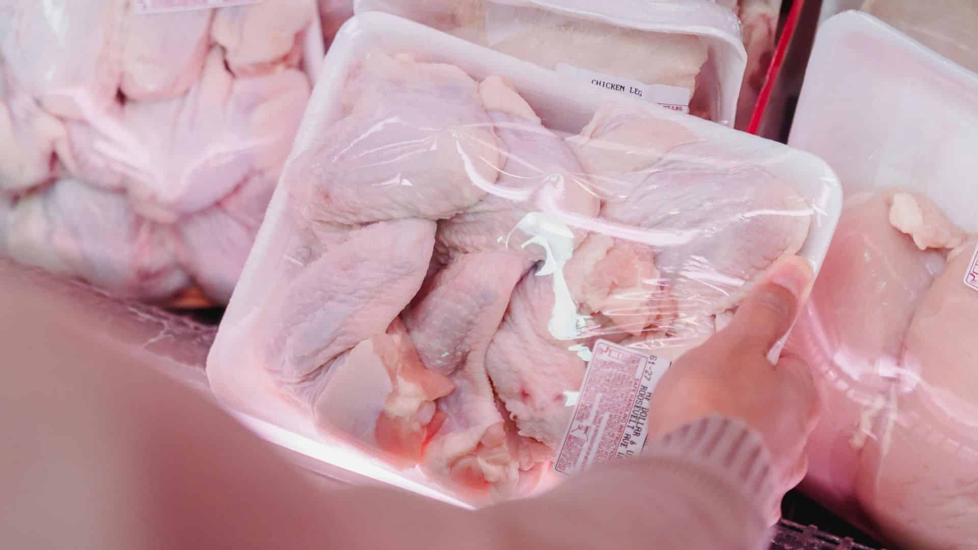 Woman wearing a mask while shopping for packaged meat at a grocery store