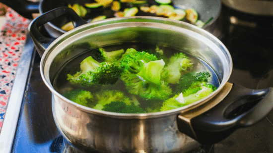Cooked broccoli pieces arranged on a white plate with herbs