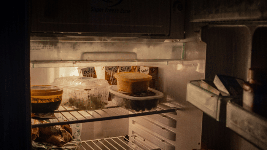 Open refrigerator with a variety of foods including fruits, drinks, and jars