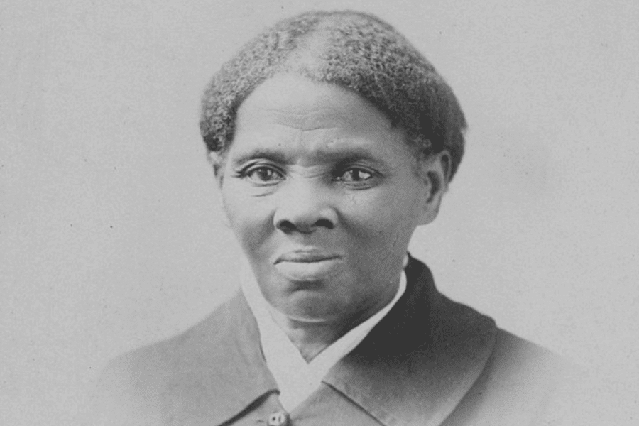 A black-and-white historical portrait of an older woman with a calm yet determined expression. She wears a dark coat with a white collar, her hair neatly pulled back. The simple background emphasizes her strong features and resolute gaze.