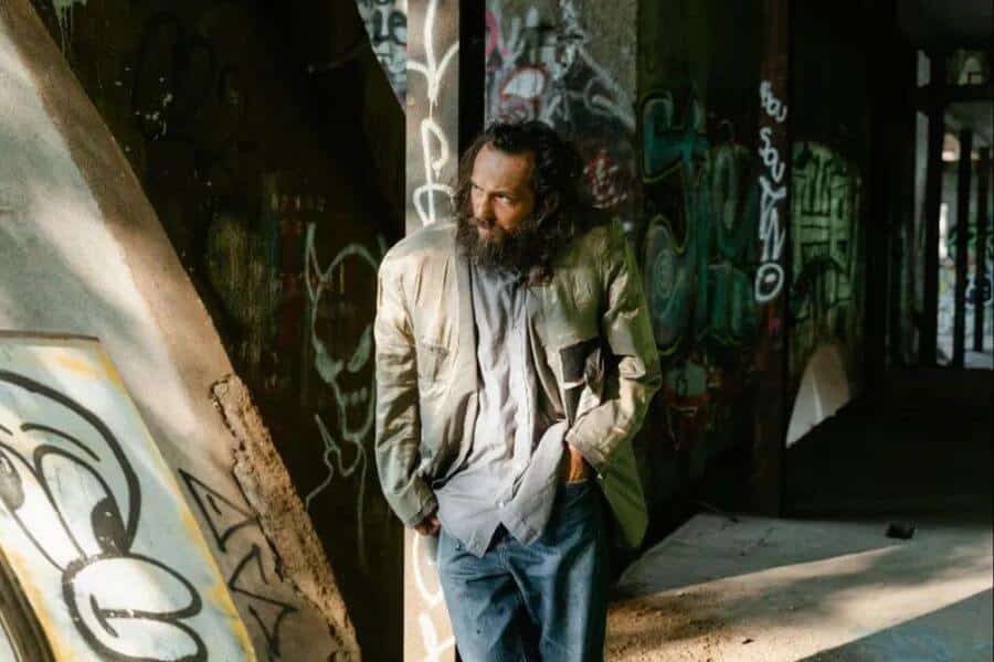 homeless man standing next to a column