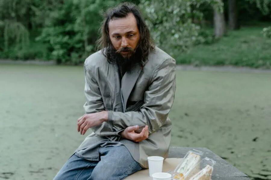 homeless man sitting o a park bench