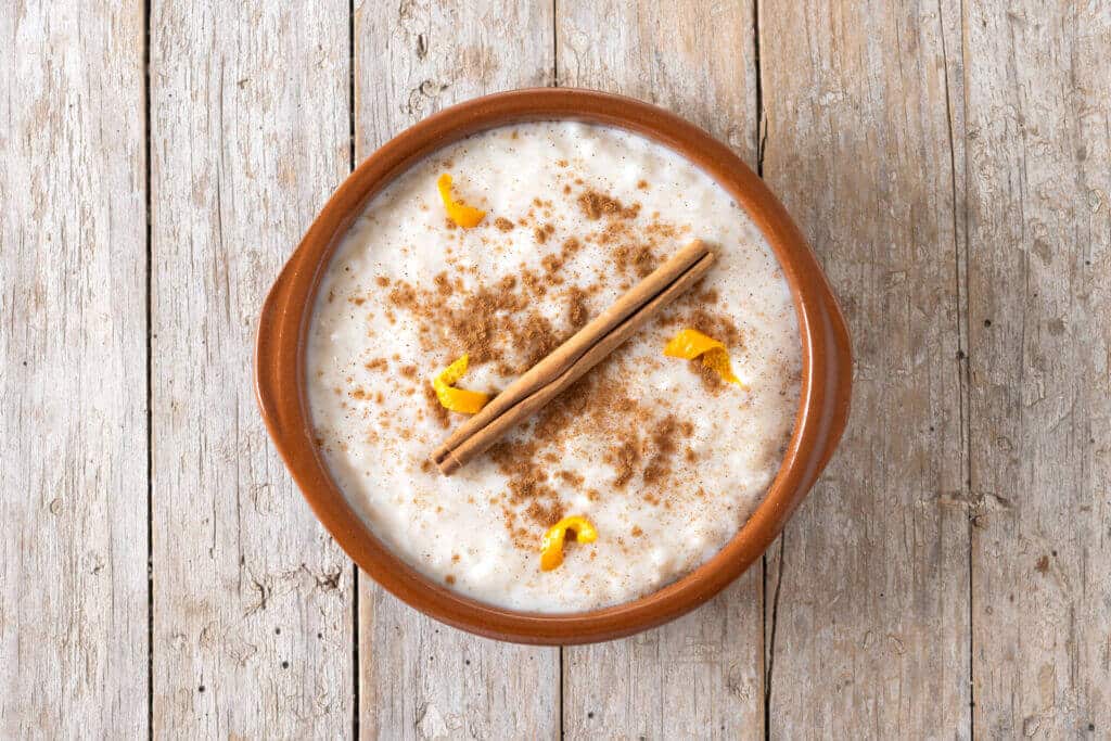 Arroz con leche with cinnamon in clay bowl on wooden table