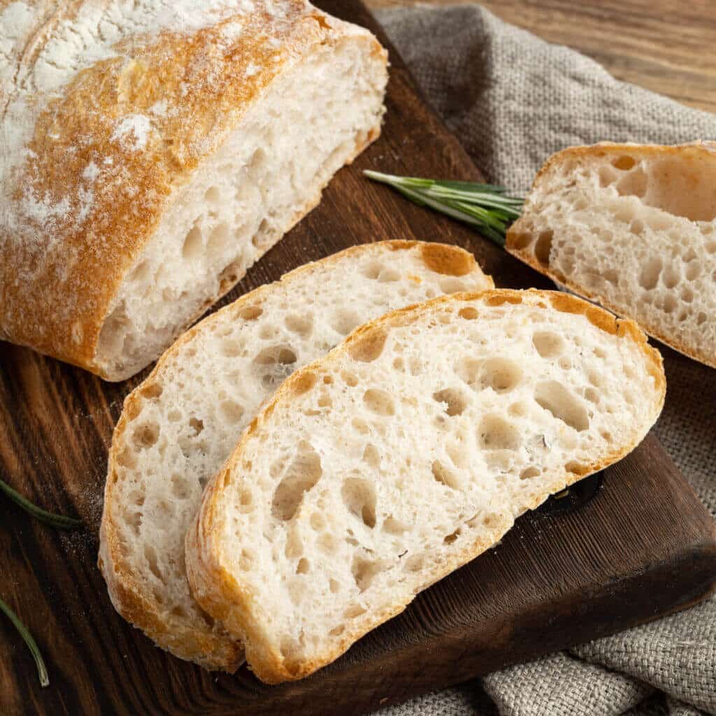 Delicious homemade sliced Italian ciabatta bread on a wooden cutting board. Close-up.