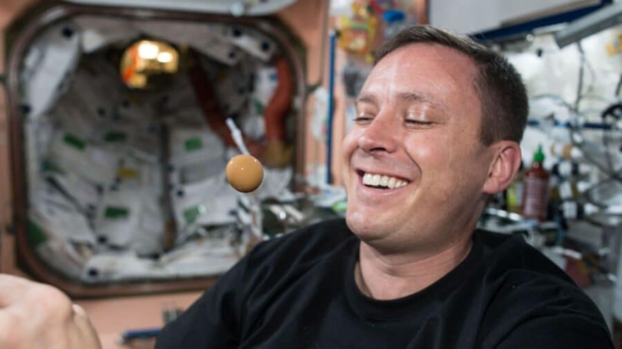 NASA astronaut Jack Fischer watches as liquid from his drink turns into a floating sphere in the weightless environment of microgravity.