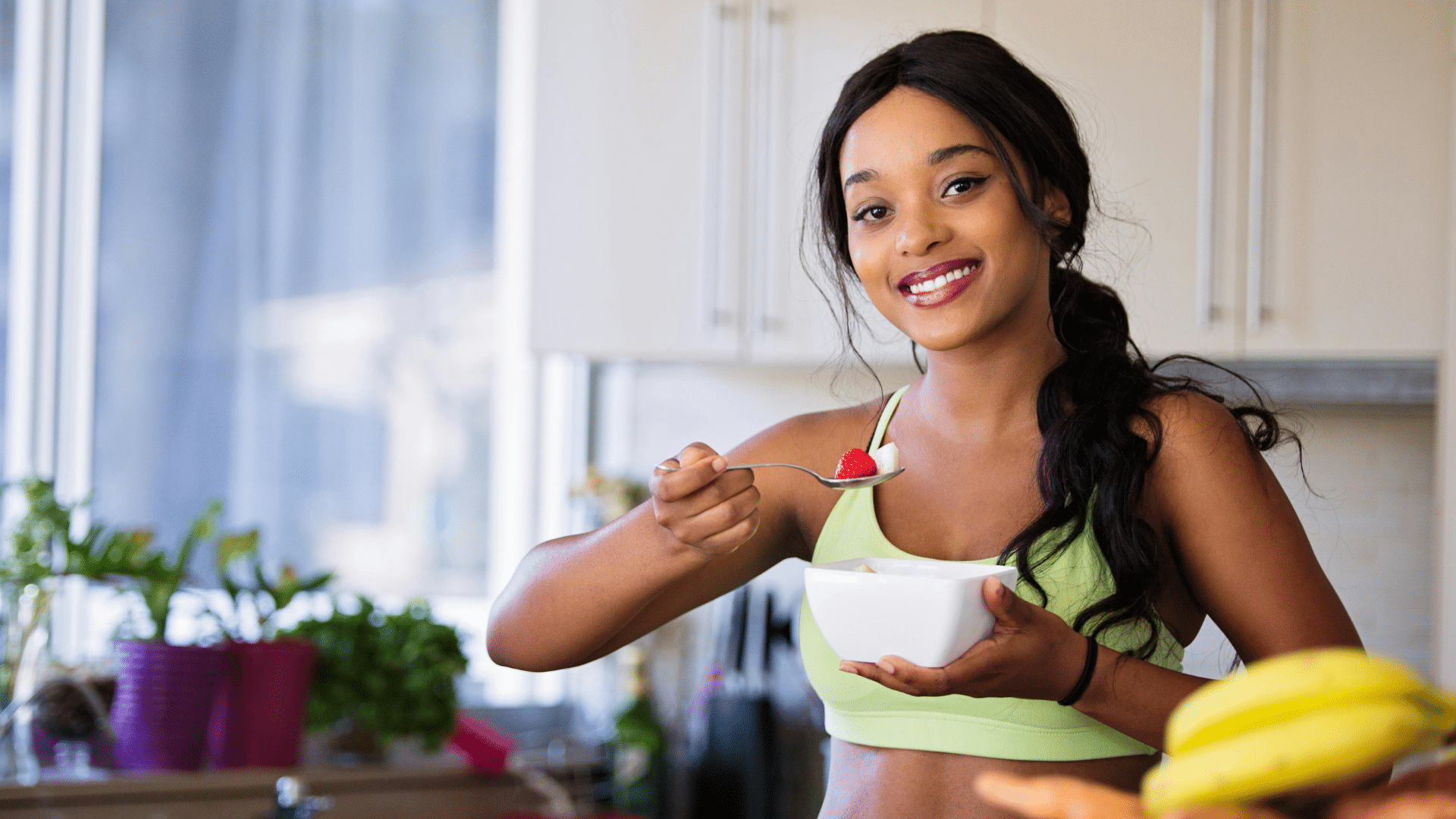 Woman smiling and holding a spoon during a meal
