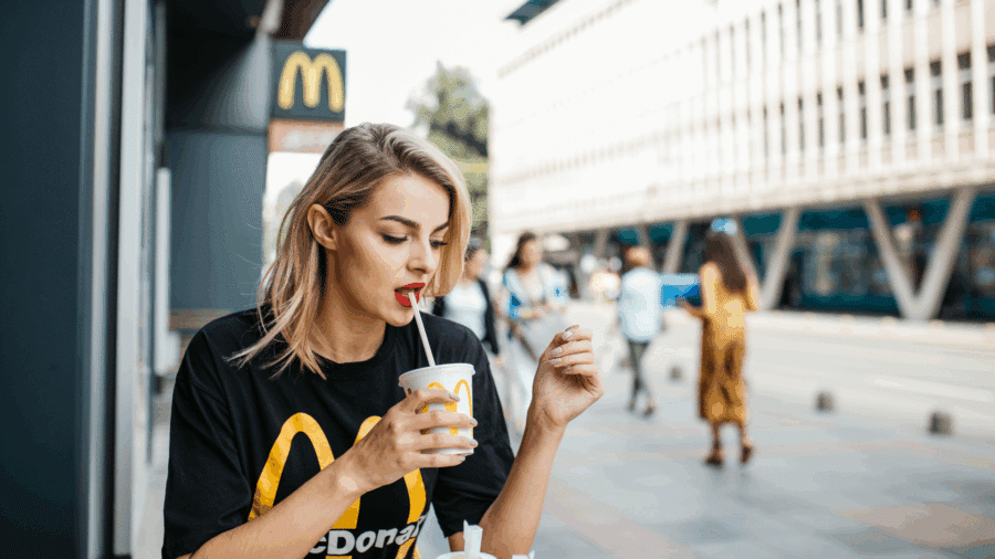 Young woman sitting outside a McDonald’s holding a drink cup