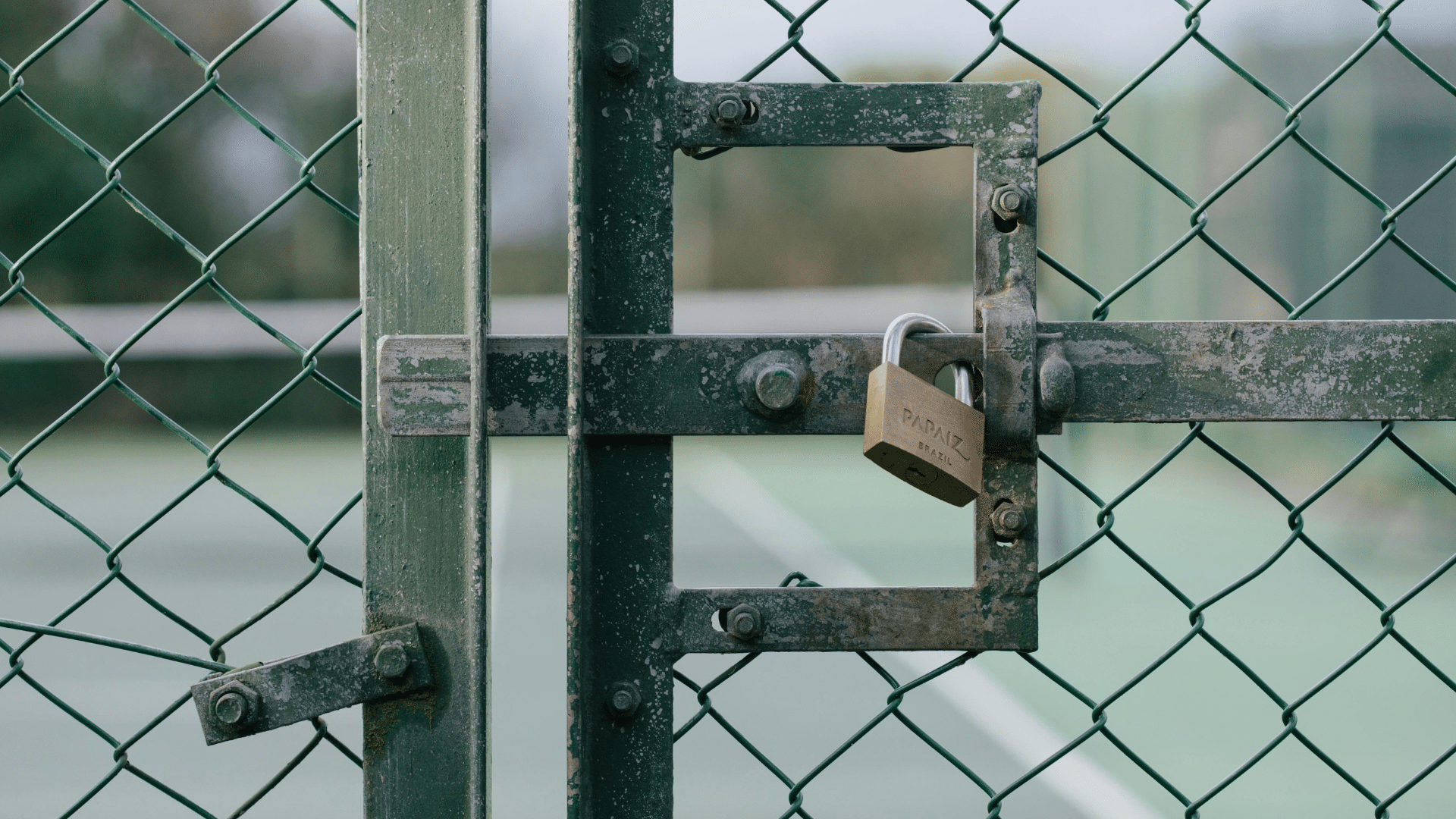 Rusty padlock on chain link fence at industrial site