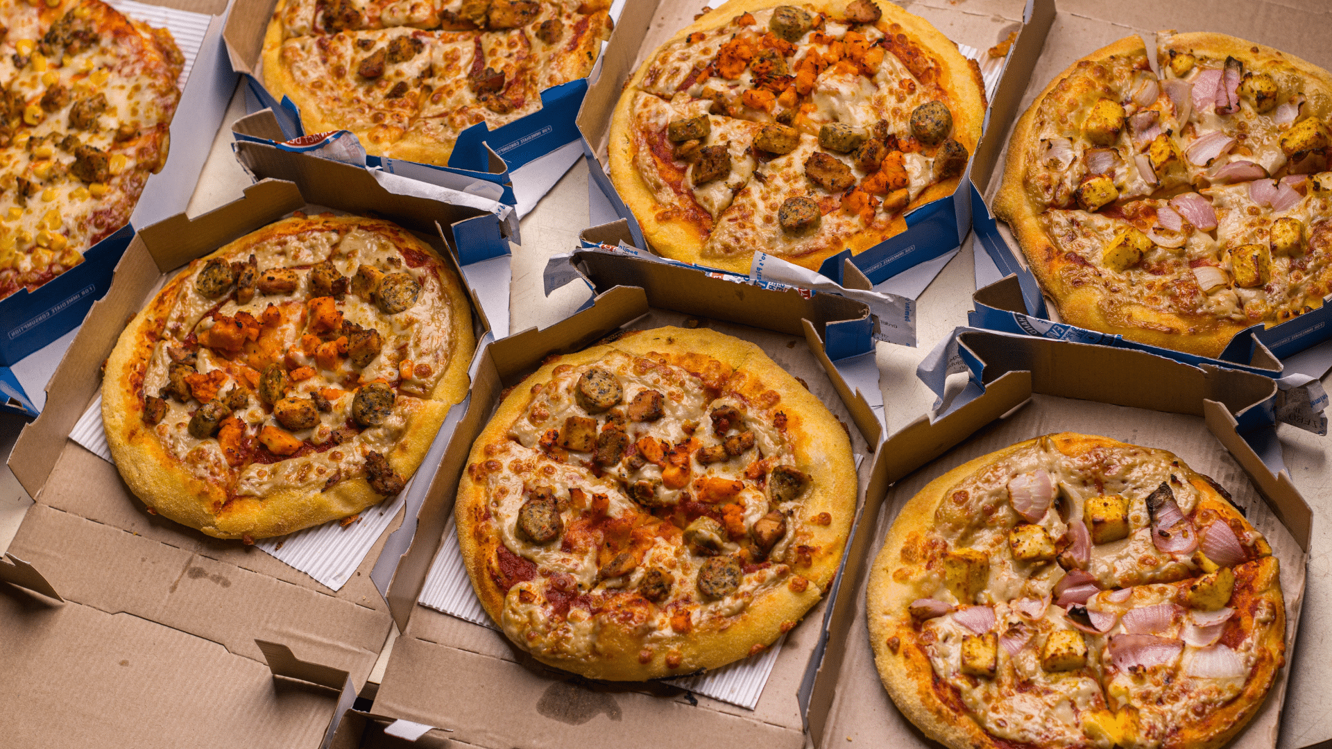 Domino’s pizza with cheese and toppings in branded delivery box