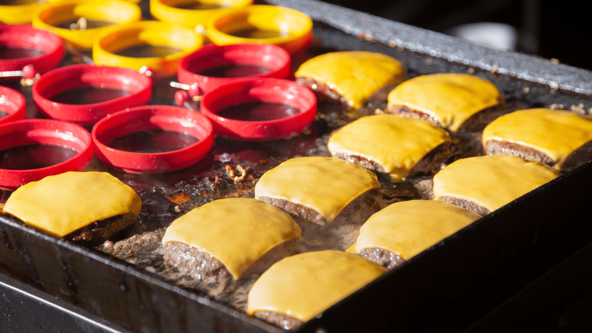 Outdoor griddle cooking cheeseburgers with melted cheese