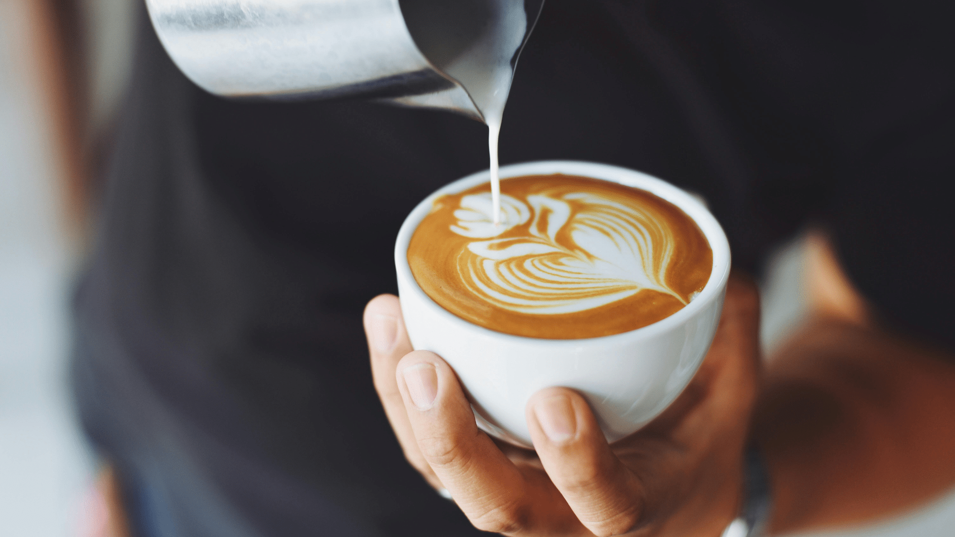 Person making latte art with milk and espresso