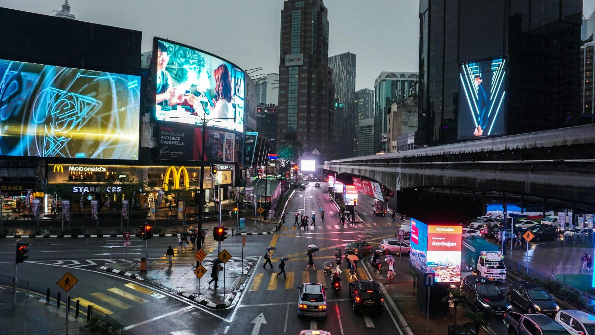 Cars driving on a city street at night with lights reflecting on the road