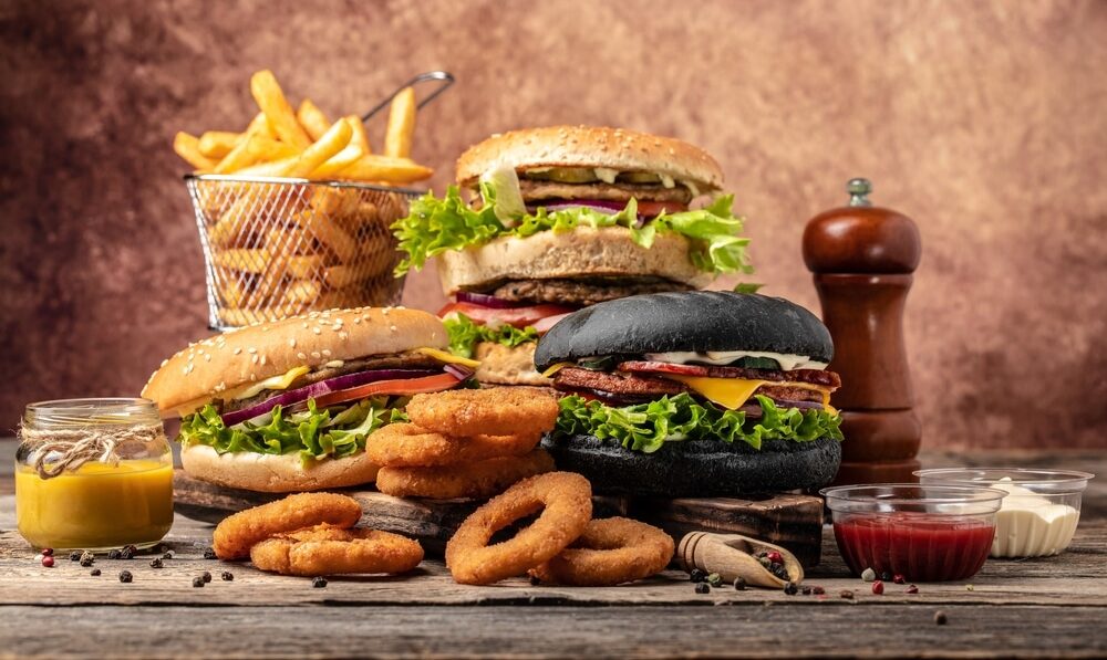 A picture showing burguers, potatoe fries, onion rings, sauces and salt.