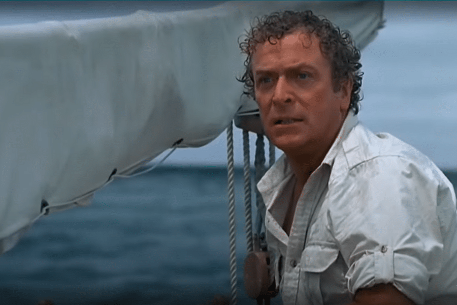A man in a white shirt stands on a boat, gripping a rope with a determined expression. The ocean and a cloudy sky form the backdrop, conveying tension.
