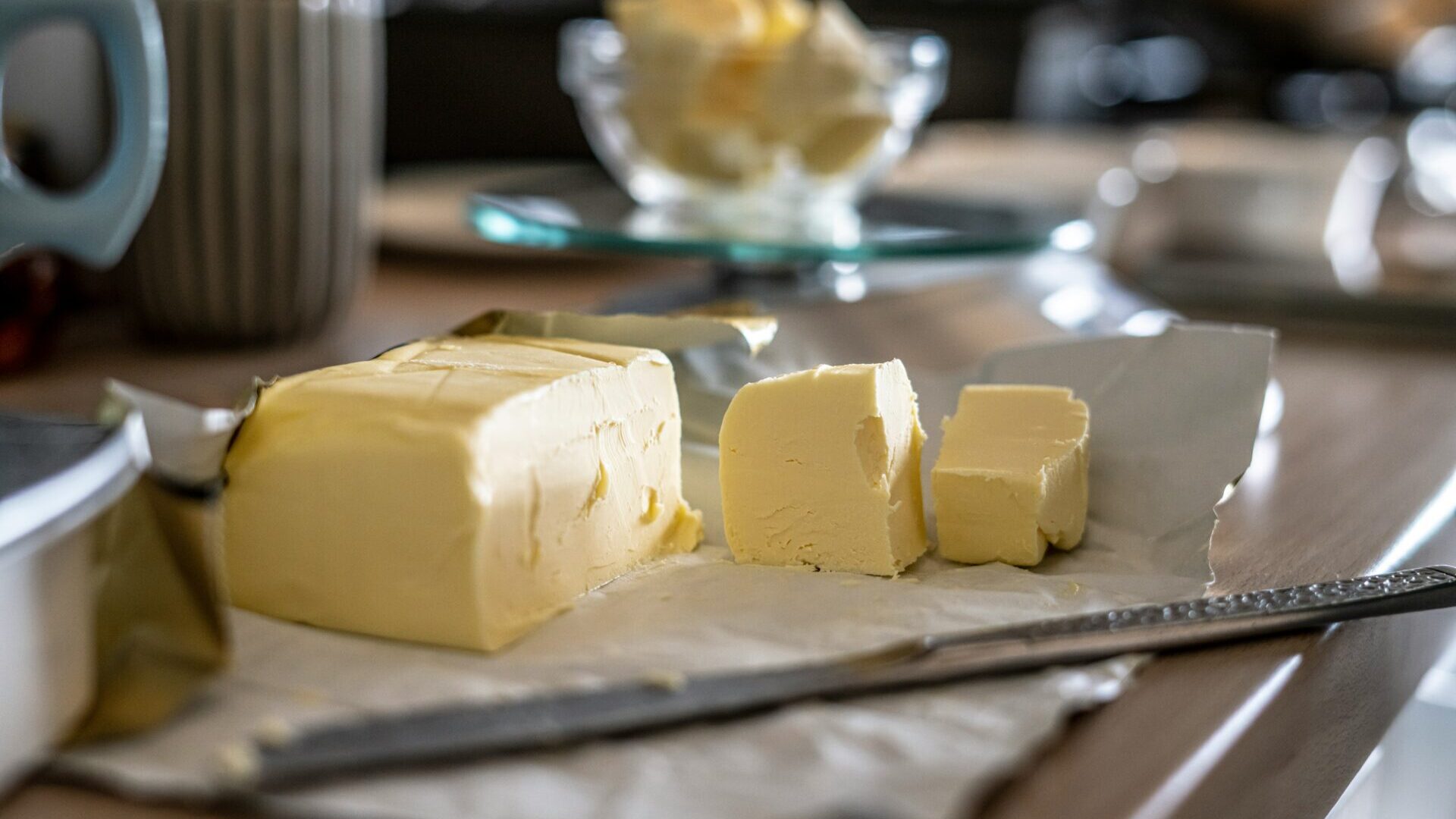 Sliced butter arranged on a clear glass plate.