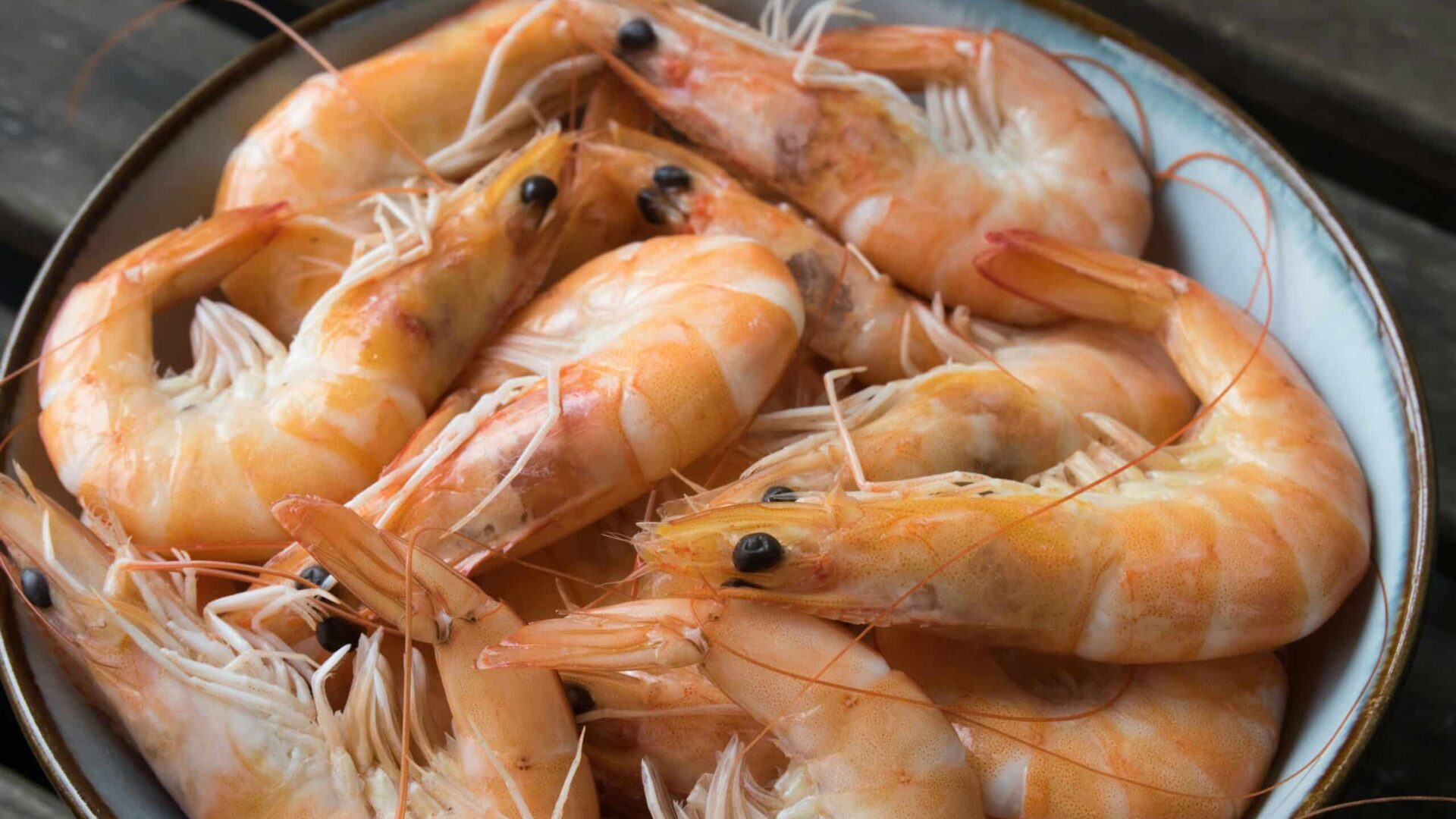 Bowl containing uncooked shrimp with shells intact.