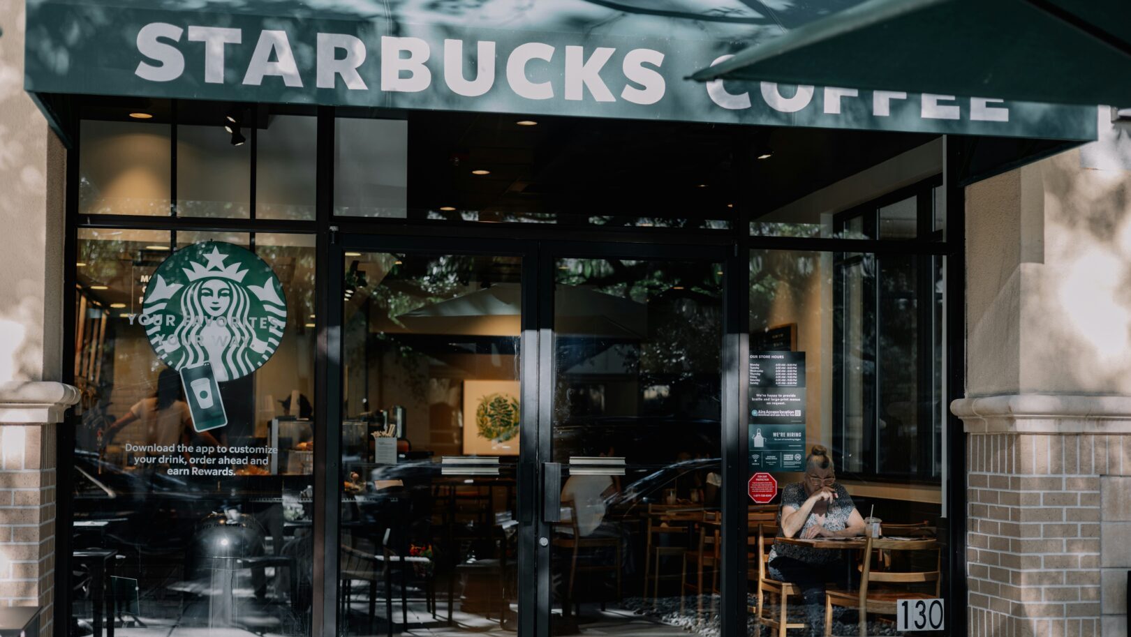 Coffee shop interior with a person seated at a table near a Starbucks counter