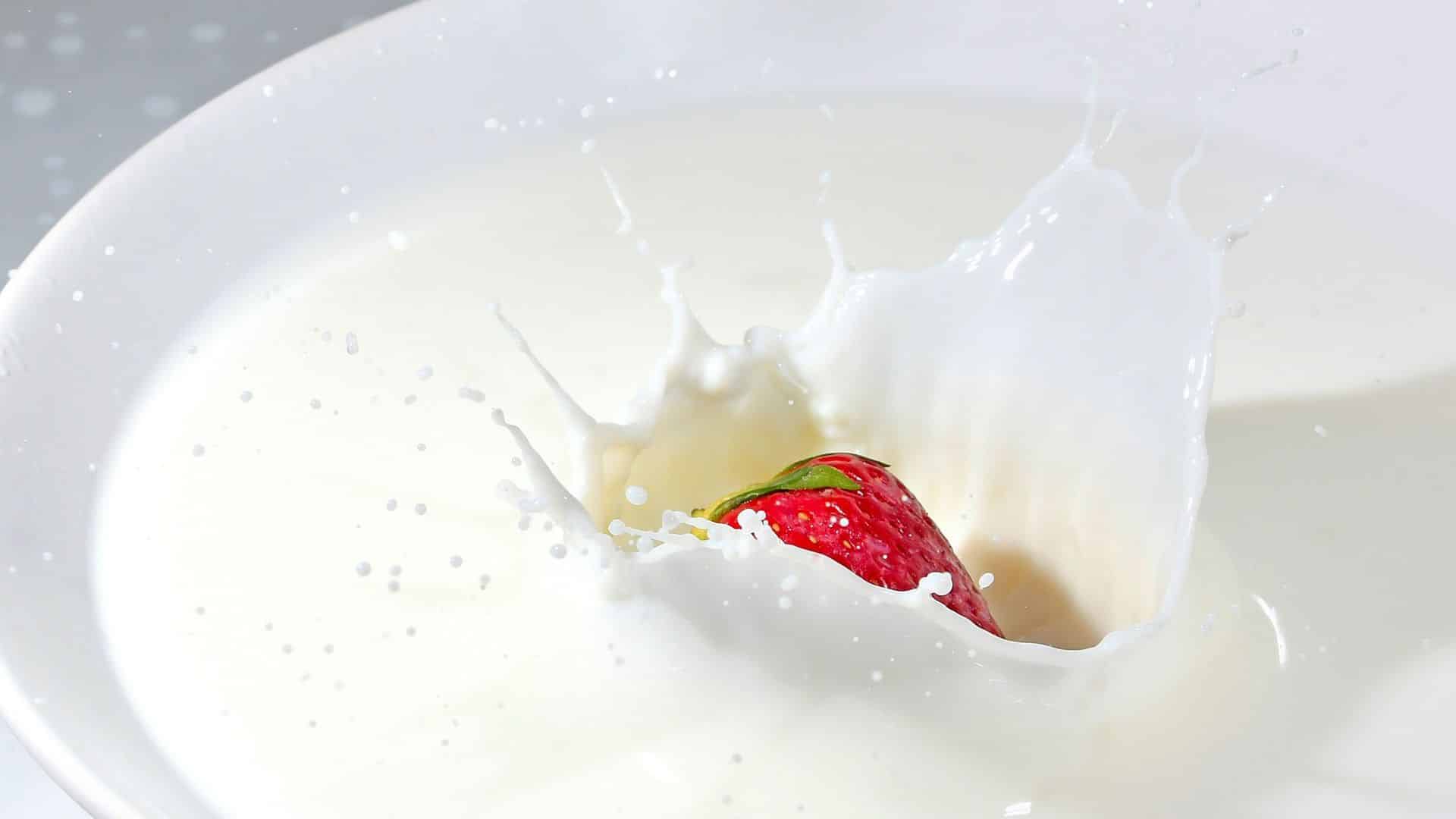 A strawberry falling into milk