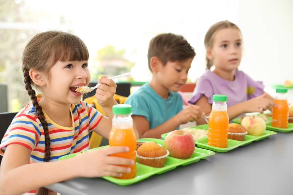 Children sitting at table and eating during break at school