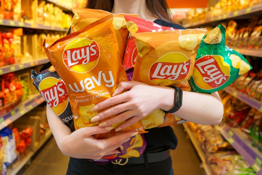 Woman's arms carrying bags of Lay's chips