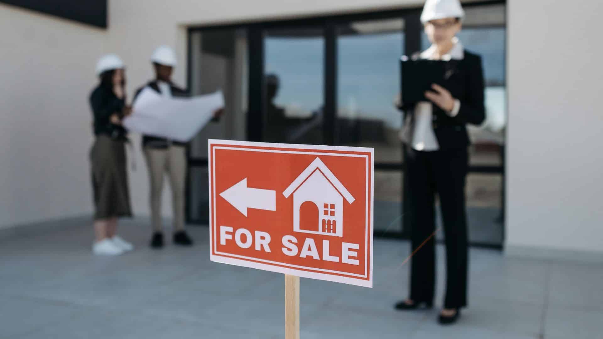 Red for sale sign placed in front of a suburban house