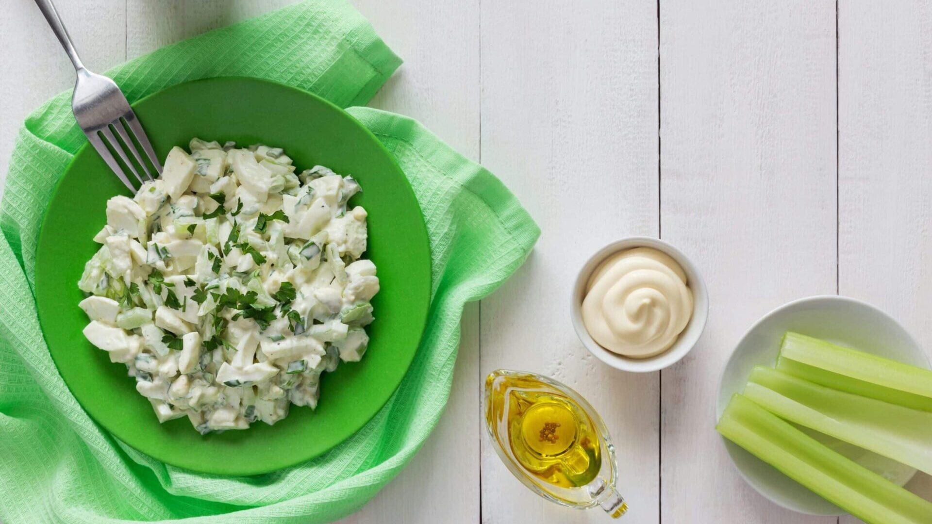 Green bowl filled with food next to a cup of tea on a table.