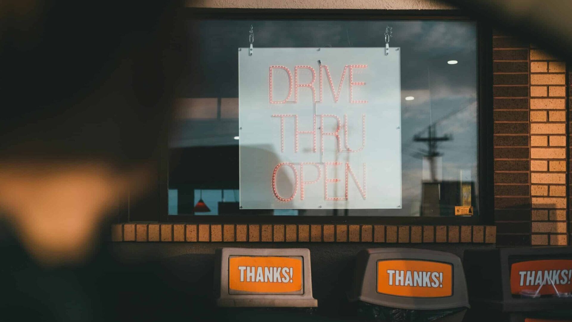 Unrecognizable man sitting in a car near a café drive-thru.