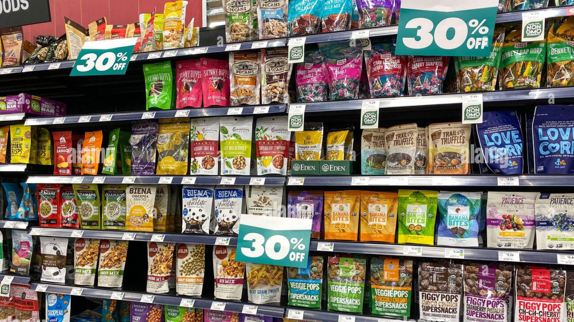 Grocery store shelf with assorted healthy snack bags and 30% off signs.