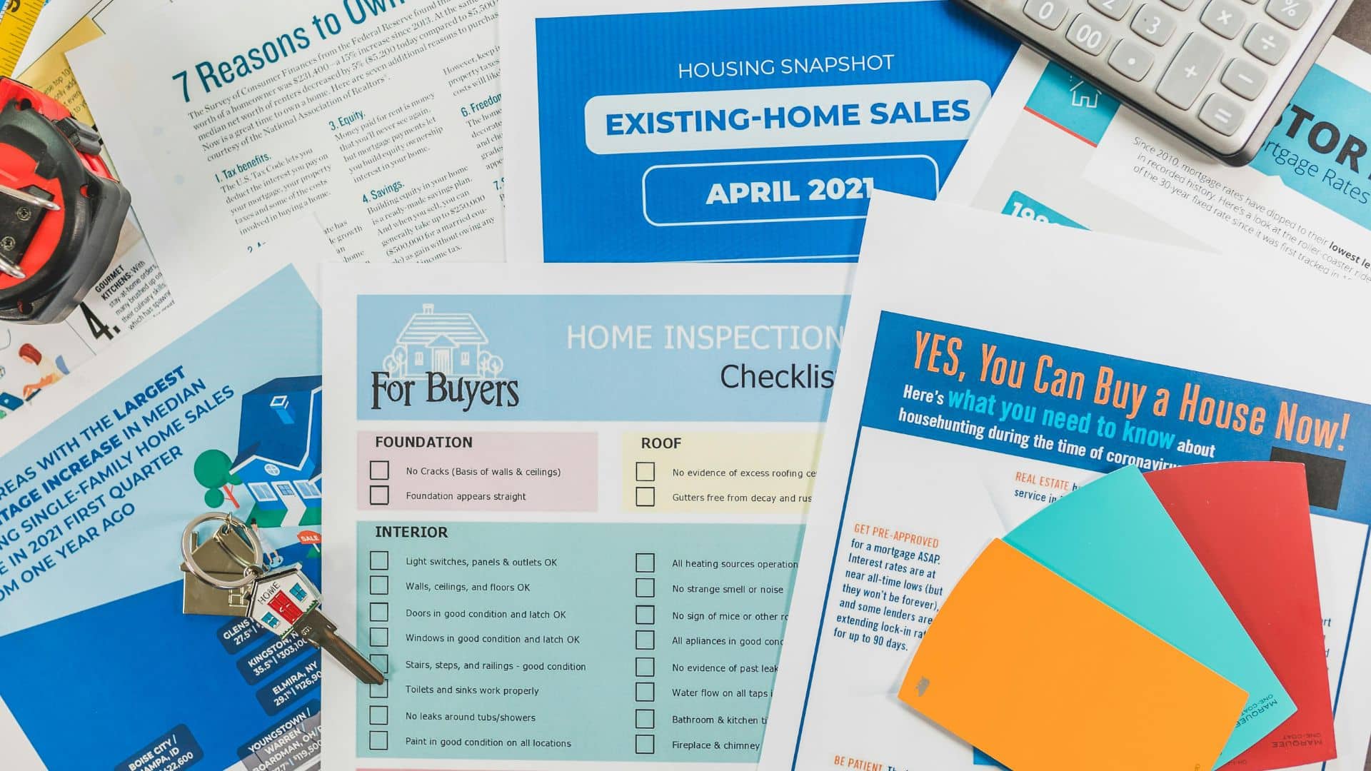 Assorted real estate brochures and flyers placed beside a calculator on a desk