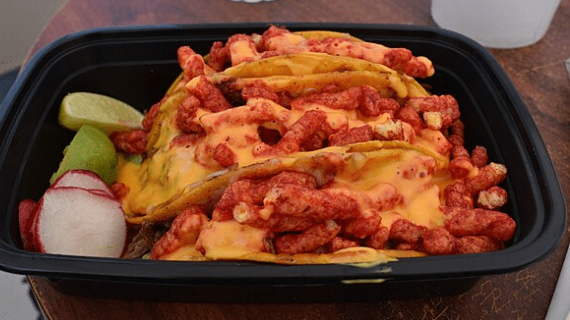 Tacos filled with Flamin’ Hot Cheetos and melted cheese, served with lime and radish slices.