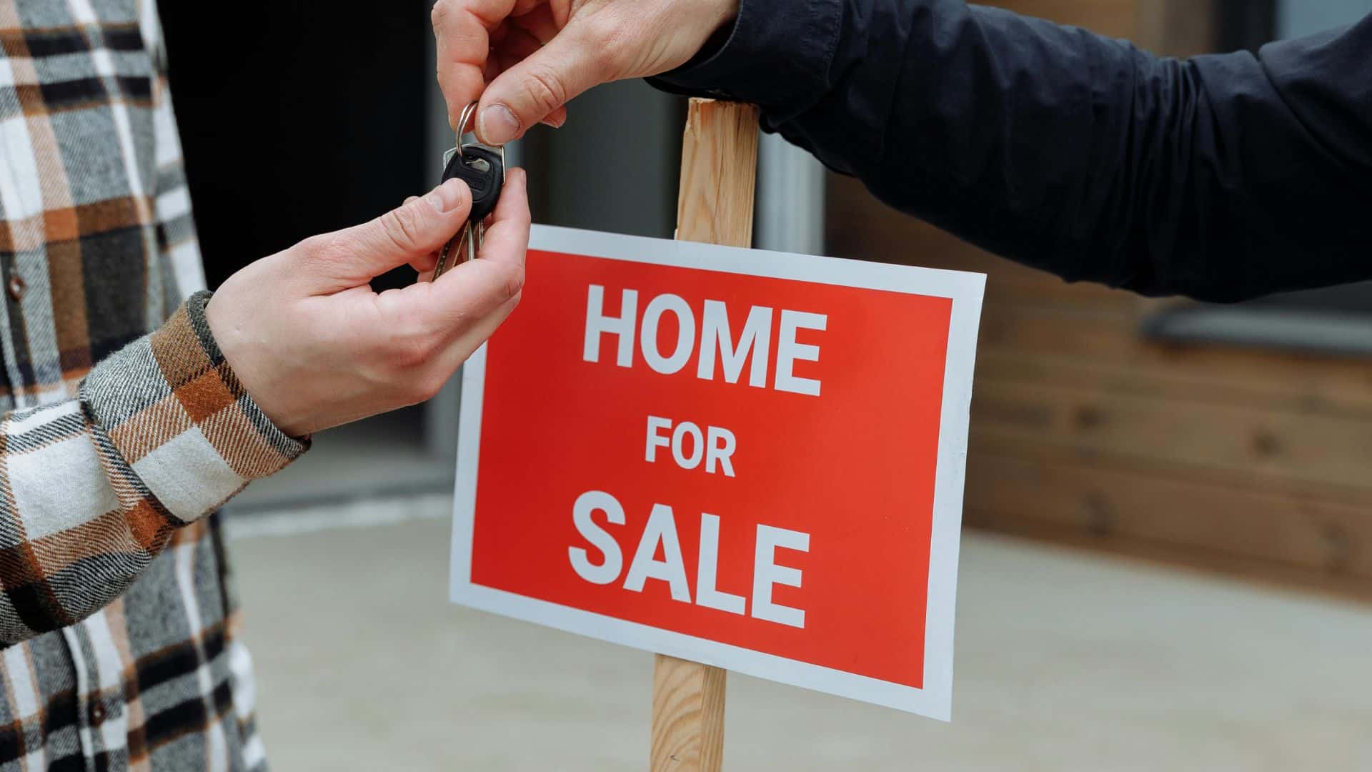 Person handing house keys to another person during a home transaction