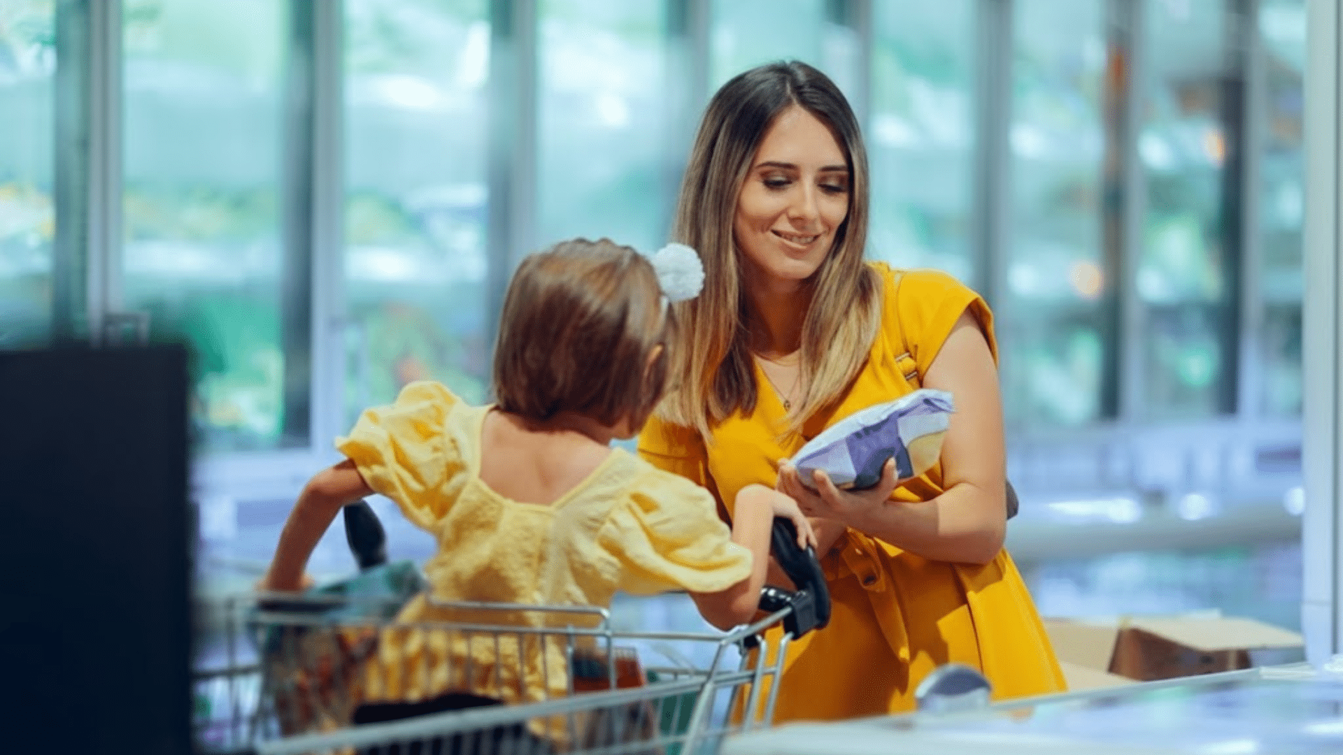 A woman and child wearing yellow clothes shopping in a grocery store aisle.