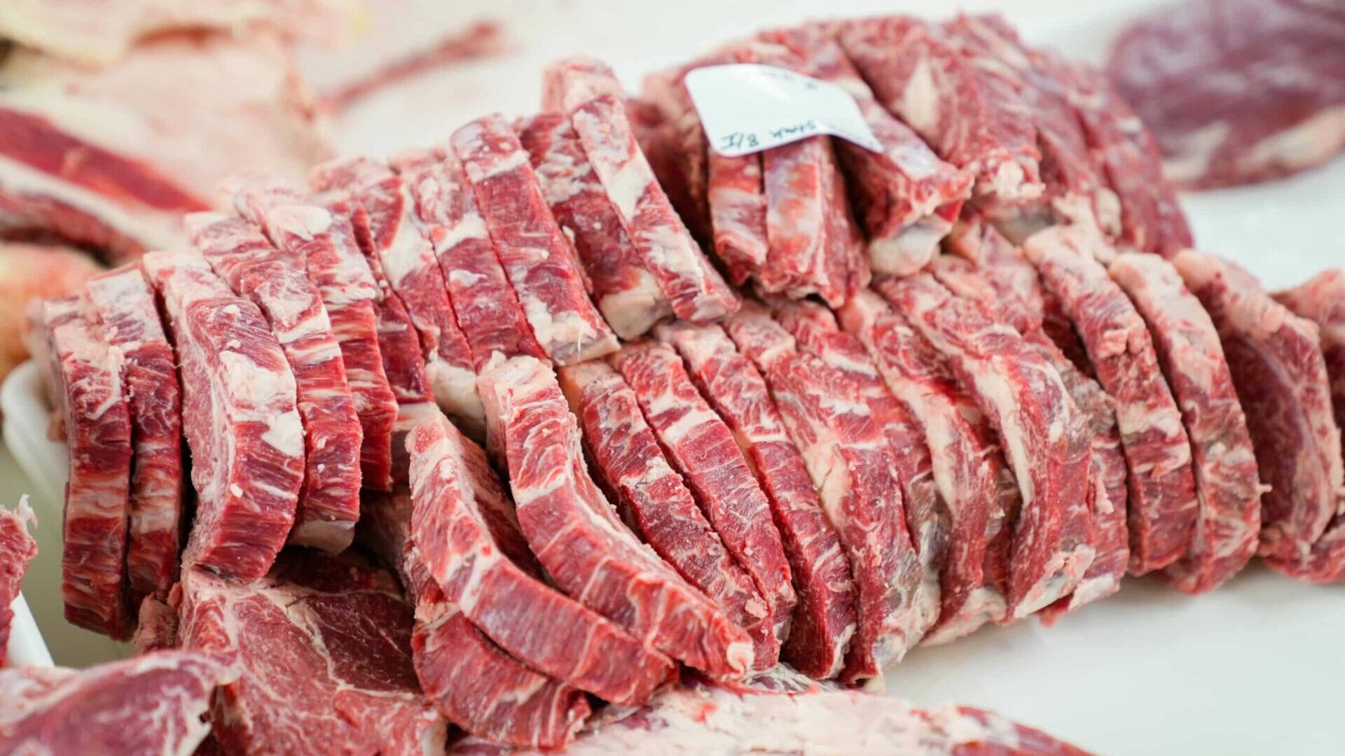 Sliced raw meat arranged on a white tray.